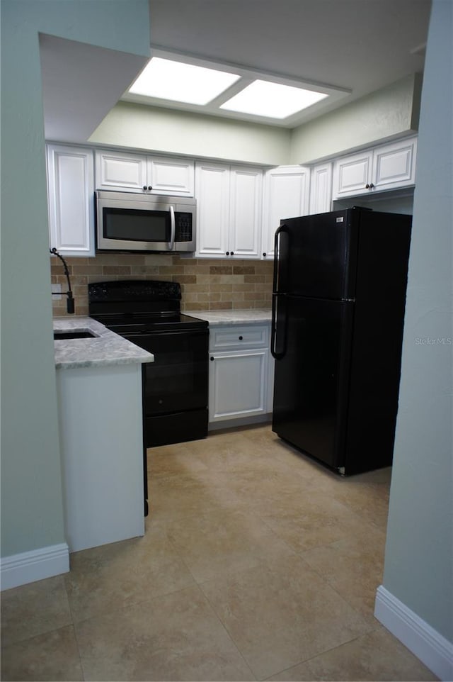 kitchen featuring black appliances, white cabinetry, and backsplash