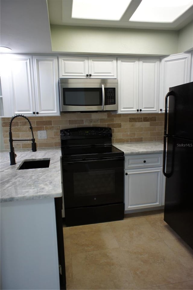 kitchen featuring black appliances, a sink, white cabinetry, tasteful backsplash, and light stone countertops