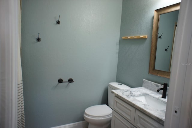 bathroom with toilet, a textured wall, and vanity
