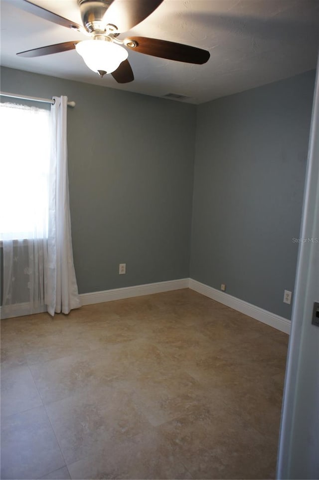 empty room with a ceiling fan and baseboards