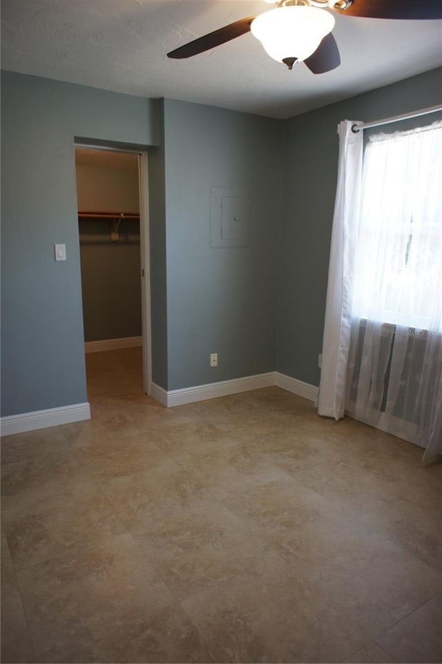 unfurnished room with ceiling fan and baseboards