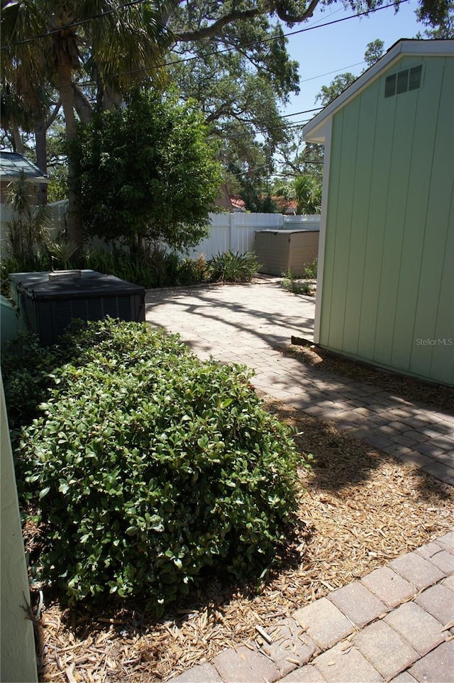 view of yard featuring fence, a shed, an outbuilding, and a patio