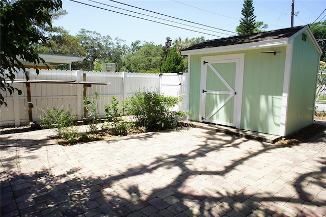 view of patio featuring a storage unit, an outbuilding, and fence