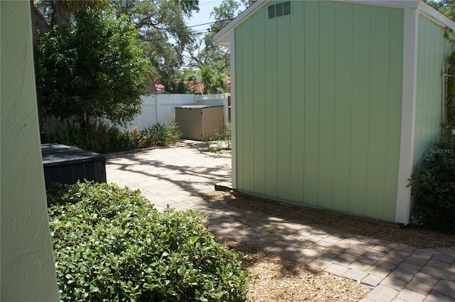 view of patio featuring a storage shed, an outbuilding, and fence