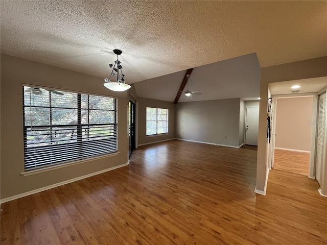 2406 Cypress Pond Rd Unit 2406, Palm Harbor, FL 34683 - unfurnished living room featuring ceiling fan, light wood-style flooring, a textured ceiling, baseboards, and vaulted ceiling