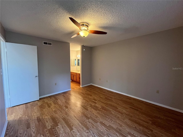 2406 Cypress Pond Rd Unit 2406, Palm Harbor, FL 34683 - unfurnished bedroom featuring wood finished floors, a textured ceiling, baseboards, ensuite bathroom, and ceiling fan