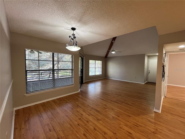 2406 Cypress Pond Rd Unit 2406, Palm Harbor, FL 34683 - unfurnished dining area with lofted ceiling, wood finished floors, ceiling fan, a textured ceiling, and baseboards