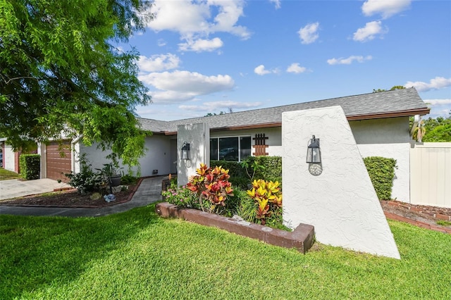 view of front facade with a front yard, stucco siding, an attached garage, and concrete driveway