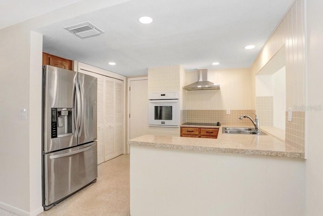 3247 Kimberly Oaks Dr, Holiday, FL 34691 - kitchen with stainless steel fridge, oven, a sink, wall chimney exhaust hood, and a peninsula