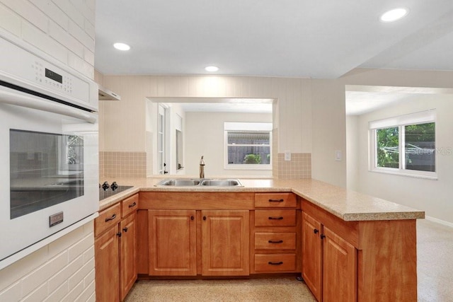 3247 Kimberly Oaks Dr, Holiday, FL 34691 - kitchen with white oven, a sink, light countertops, a peninsula, and brown cabinetry