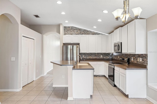 kitchen with stainless steel appliances, dark countertops, lofted ceiling, a sink, and tasteful backsplash