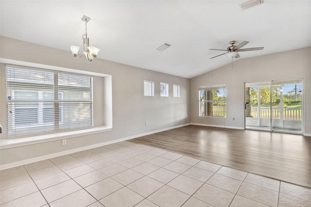spare room with a chandelier, vaulted ceiling, a ceiling fan, light wood-style flooring, and baseboards