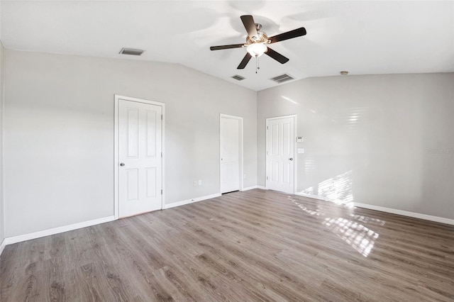 empty room featuring a ceiling fan, vaulted ceiling, wood finished floors, and baseboards