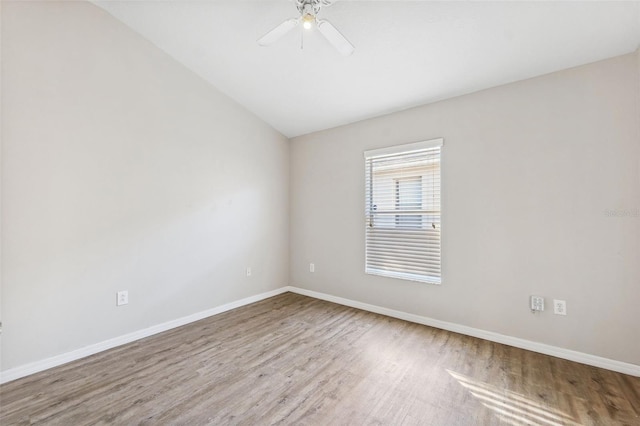 spare room with wood finished floors, lofted ceiling, baseboards, and ceiling fan