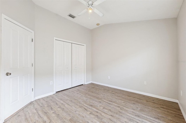 unfurnished bedroom featuring wood finished floors, baseboards, a closet, and vaulted ceiling