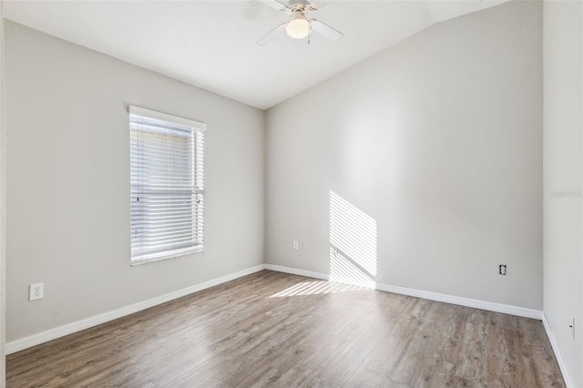 spare room featuring lofted ceiling, wood finished floors, baseboards, and ceiling fan