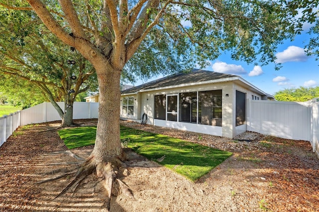 rear view of property with a sunroom and stucco siding