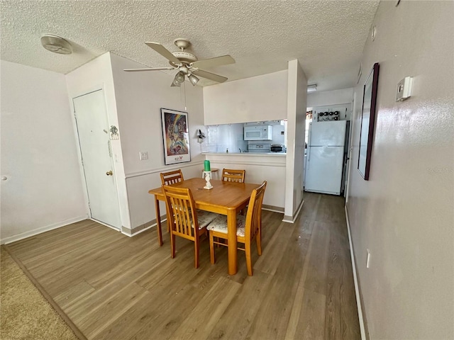320 Medallion Blvd Unit G, Madeira Beach, FL 33708 - dining space with wood finished floors, a ceiling fan, a textured ceiling, and baseboards