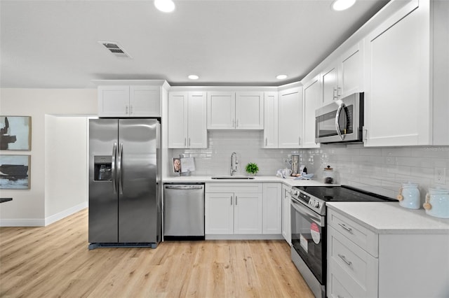 4549 Ontario Dr, New Port Richey, FL 34652 - kitchen with appliances with stainless steel finishes, a sink, white cabinets, decorative backsplash, and recessed lighting