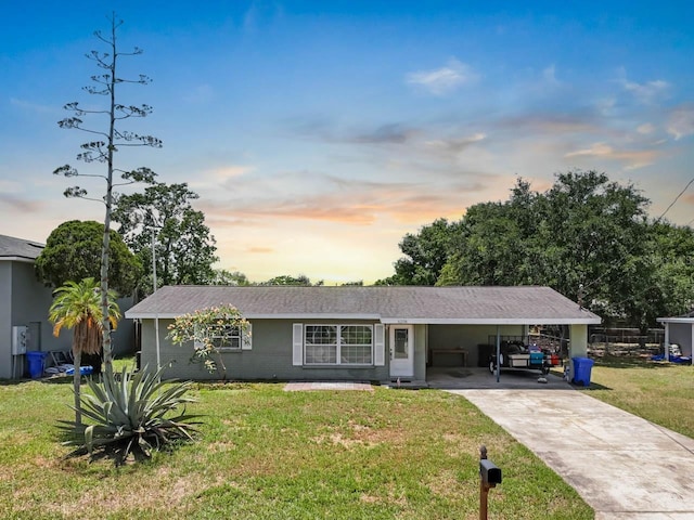 single story home featuring a front lawn, concrete driveway, and a carport