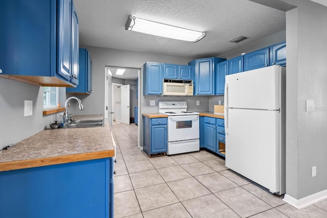 kitchen with white appliances, a sink, blue cabinets, light tile patterned floors, and a textured ceiling