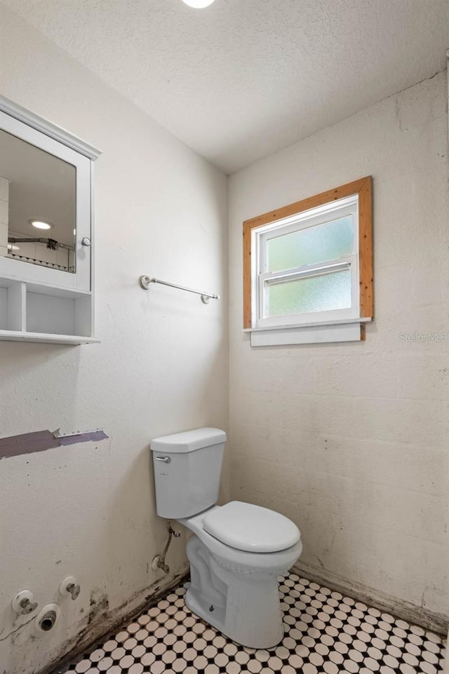 bathroom with toilet, tile patterned floors, and a textured ceiling