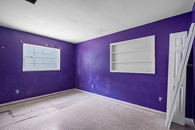 unfurnished room featuring baseboards and built in shelves