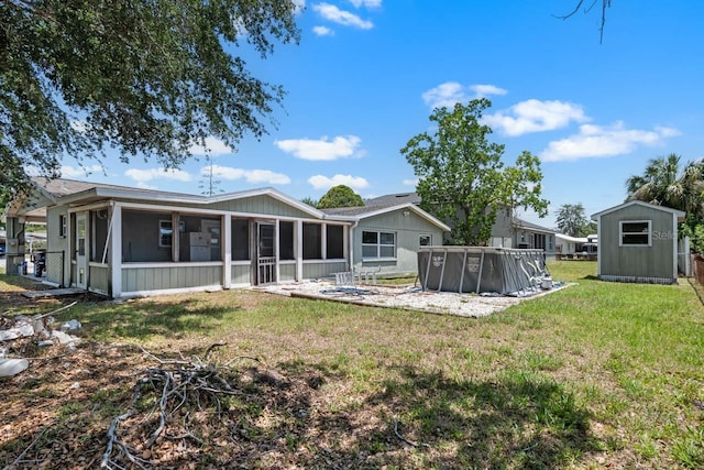 back of house with a sunroom, a storage unit, an outdoor pool, an outdoor structure, and a lawn