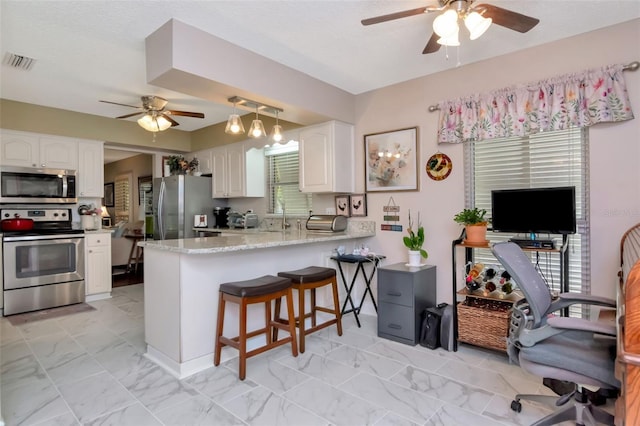 4125 W Obispo St, Tampa, FL 33629 - kitchen with stainless steel appliances, ceiling fan, white cabinetry, a peninsula, and light marble finish flooring
