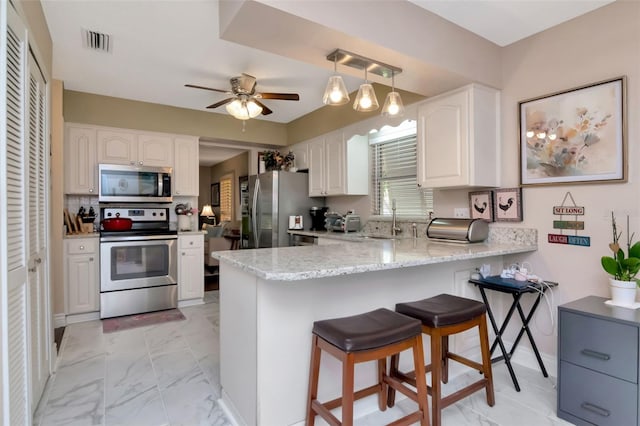 4125 W Obispo St, Tampa, FL 33629 - kitchen featuring appliances with stainless steel finishes, a peninsula, light marble finish flooring, and white cabinetry
