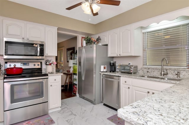 4125 W Obispo St, Tampa, FL 33629 - kitchen featuring appliances with stainless steel finishes, a sink, a ceiling fan, light marble finish flooring, and white cabinets