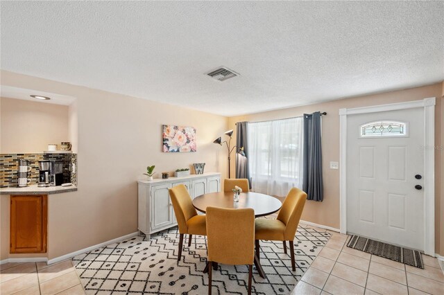 8497 Portulaca Ave, Seminole, FL 33777 - dining space with light tile patterned flooring, a textured ceiling, and baseboards