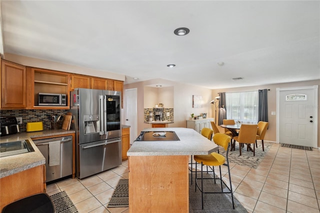 8497 Portulaca Ave, Seminole, FL 33777 - kitchen featuring appliances with stainless steel finishes, light tile patterned floors, a kitchen island, open shelves, and recessed lighting