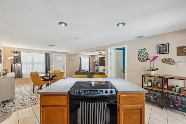 8497 Portulaca Ave, Seminole, FL 33777 - kitchen with electric range, light tile patterned flooring, open floor plan, a center island, and a ceiling fan
