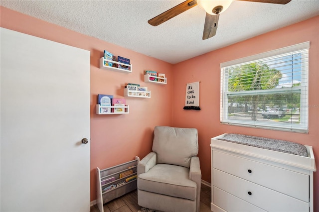 8497 Portulaca Ave, Seminole, FL 33777 - living area featuring a textured ceiling, a ceiling fan, wood finished floors, and baseboards