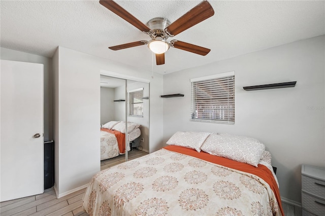 8497 Portulaca Ave, Seminole, FL 33777 - bedroom featuring a closet, light wood finished floors, a ceiling fan, baseboards, and a textured ceiling