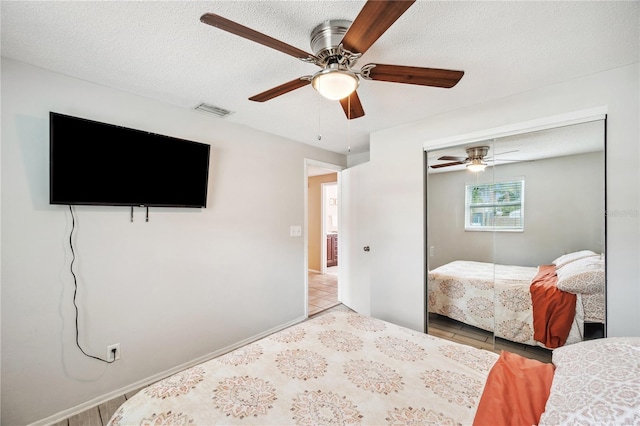 8497 Portulaca Ave, Seminole, FL 33777 - tiled bedroom with ceiling fan, a closet, and a textured ceiling
