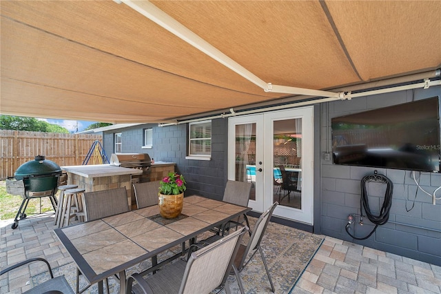 8497 Portulaca Ave, Seminole, FL 33777 - view of patio / terrace featuring an outdoor kitchen, area for grilling, french doors, fence, and outdoor dining space