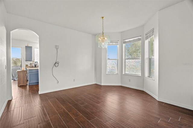 2832 Brinley Dr, New Port Richey, FL 34655 - empty room featuring arched walkways, plenty of natural light, dark wood-style floors, and baseboards
