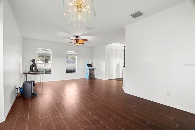 2832 Brinley Dr, New Port Richey, FL 34655 - unfurnished living room with dark wood-type flooring, a chandelier, ceiling fan, and baseboards