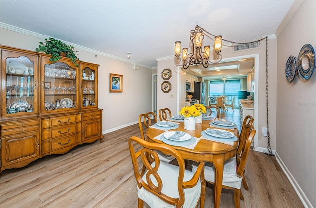 1600 Gulf Blvd Unit 514, Clearwater Beach, FL 33767 - dining room with light wood-style floors, a chandelier, crown molding, and baseboards