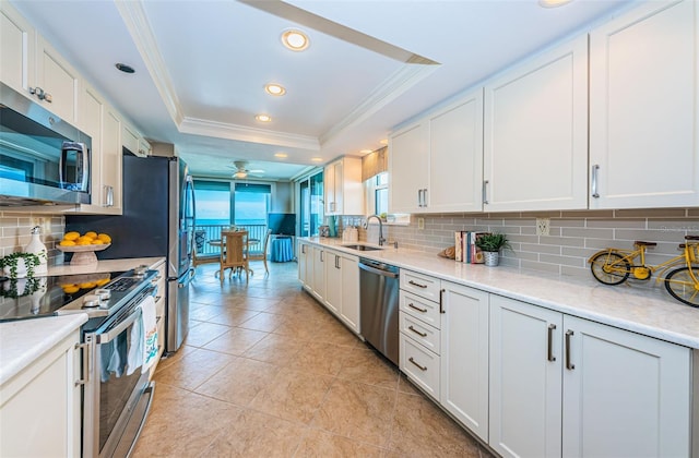 1600 Gulf Blvd Unit 514, Clearwater Beach, FL 33767 - kitchen featuring stainless steel appliances, crown molding, a tray ceiling, a sink, and decorative backsplash