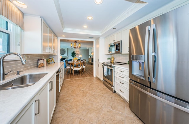 1600 Gulf Blvd Unit 514, Clearwater Beach, FL 33767 - kitchen with stainless steel appliances, a sink, a tray ceiling, ornamental molding, and white cabinets