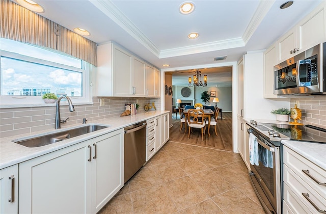 1600 Gulf Blvd Unit 514, Clearwater Beach, FL 33767 - kitchen with stainless steel appliances, a sink, ornamental molding, a raised ceiling, and decorative backsplash