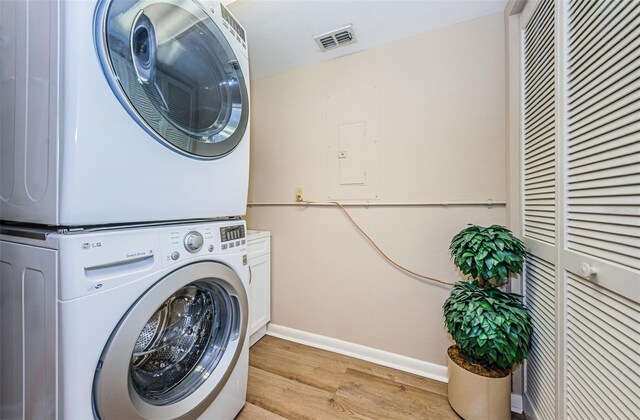 1600 Gulf Blvd Unit 514, Clearwater Beach, FL 33767 - laundry room with stacked washer / dryer, cabinet space, light wood-style flooring, and baseboards