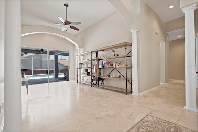empty room with ceiling fan, arched walkways, decorative columns, lofted ceiling, and baseboards