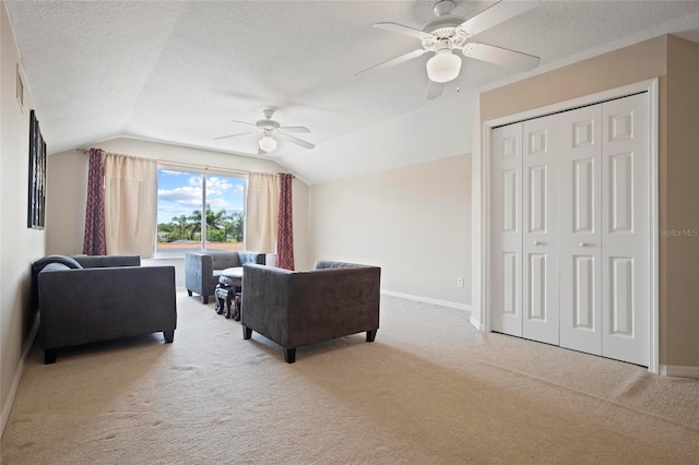 carpeted living room with a ceiling fan, vaulted ceiling, a textured ceiling, and baseboards