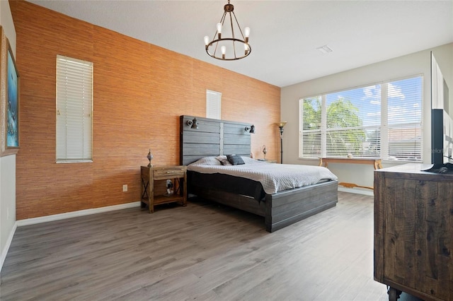 bedroom featuring baseboards, wood finished floors, and a chandelier