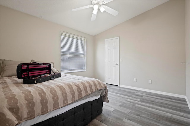 bedroom featuring wood finished floors, lofted ceiling, baseboards, and a ceiling fan