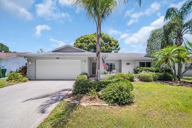 2113 Malcolm Dr, Palm Harbor, FL 34684 - ranch-style home with an attached garage, concrete driveway, a front lawn, and stucco siding